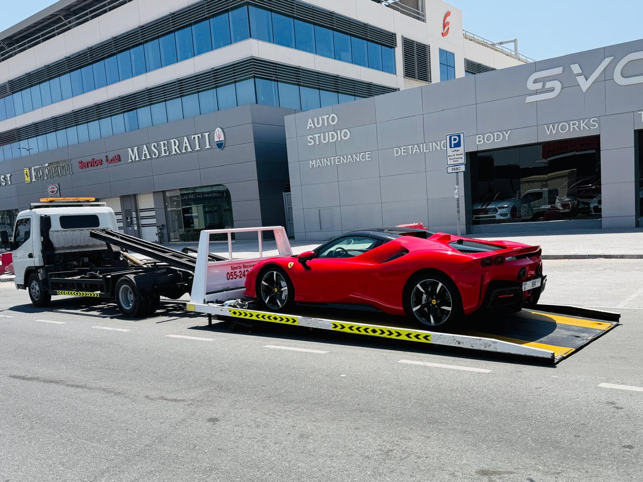 Luxury sports car recovery Dubai - Ferrari on flatbed outside Dubai auto studio